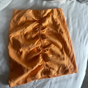 Orange kjol från Zara - Säljer en superfin orange kjol från Zara i storlek s. Kjolen har en snygg rynkad detalj framtill som ger en cool look. Perfekt för sommardagar eller en utekväll! 🧡 kjolen kan även användas som topp!