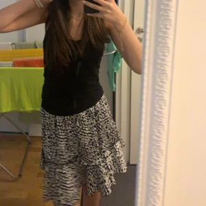 Ursnygg svartvit mönstrad kjol - Säljer en superfin svartvit kjol med volanger. Den har ett coolt mönster som påminner om leopard och är perfekt för både vardag och fest. Kjolen är kort och har en elastisk midja för en bekväm passform. Passar perfekt till sommaren eller våren! 🖤🤍Pris kan diskuteras! 