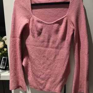 Rosa stickad tröja - Säljer en superfin rosa stickad tröja med fyrkantig urringning. Den är långärmad och har en figurnära passform som är perfekt för både vardag och fest. Tröjan är mjuk och bekväm, perfekt för kyligare dagar. Passar bra till jeans eller kjol!