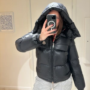 Svart dunjacka från Moncler - Snygg och varm svart dunjacka från Moncler med huva och dragkedja. Perfekt för kyliga dagar. Använd två säsonger i bra skick. Köpte i herrmodell då jag ville ha en mer lose modell. Orginalpris 20 185 kr.