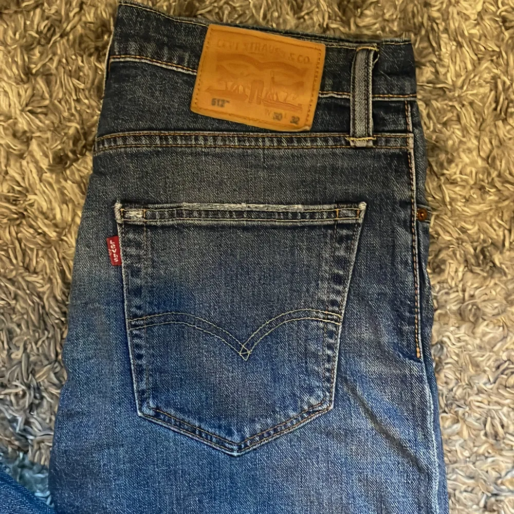 Säljer ett par klassiska blå Levi's jeans i bra skick. De har en liten slitagefläck på benet men är annars i fint skick. Perfekta för vardagsbruk med en snygg straight passform och midwaist. Passar både till avslappnade och mer uppklädda tillfällen.. Jeans & Byxor.