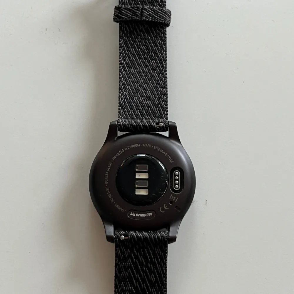 Smartwatch från Garmin, modell Vivomove style, 42 mm. Grafitfärgat aluminiumhölje med svartfärgat vävt nylonarmband. I mycket bra skick, enstaka små ytliga slitage (se bilder), fullt fungerande. Kommer med laddare.   Mer info: https://www.garmin.com/sv-SE/p/662825/pn/010-02240-03. Accessoarer.