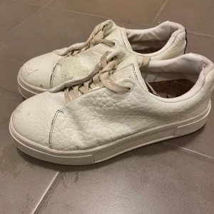 Vita sneakers från Eytys - Säljer ett par vita sneakers från Eytys i skinn med gummisula. Skorna har snörning och en mörk rand på hälen. De är i acceptabelt skick med lite slitage på ytan och sulan. Modellen heter ”eytys doja sneakers white tumbled leather”, nypris är 2099kr, säljer för 400kr🫶🏻