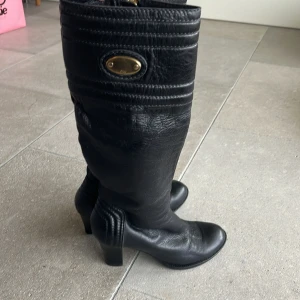 Chloe Svarta stövlar med klack  - Snygga svarta stövlar i skinn med klack och dragkedja. De har en elegant design med gulddetaljer och quiltade sömmar. Perfekta för höst och vinter, både till vardags och fest. Skorna är i mycket bra skick och är från Chloe! Storlek 38❣️❣️