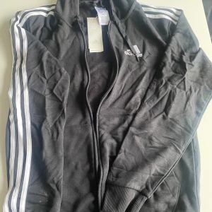 Oanvänd Adidas munkjacka med prislapp kvar - Svartare än vad det ser ut som på bilden. Aldrig använd. Stl S