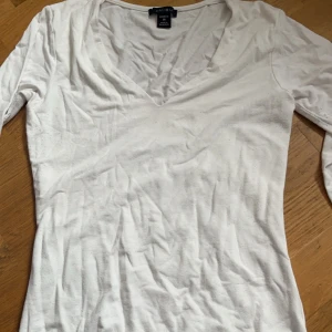 Vit långärmad topp från H&M - Säljer en enkel och stilren vit långärmad topp från New yorker . Den har en v-ringad hals och är perfekt för både vardag och fest. Materialet är mjukt och bekvämt, vilket gör den idealisk för alla säsonger. Passar bra till jeans eller kjol!