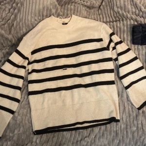 Randig tröja från H&M - Säljer en randig tröja från H&M i svart och vit. Den är stickad och har långa ärmar. Tyvärr finns det ett hål på framsidan, men annars är den i bra skick. Den är i storlek S.