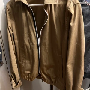 Beige jacka från BOSS - Säljer en snygg beige jacka från BOSS i regular fit. Den har en stilren design med dragkedja och långa ärmar. Perfekt för höst och vår.