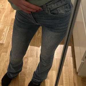 Blå bootcut jeans - Säljer ett par snygga blå bootcut jeans i bra skick. De är low waist och  har en klassisk femficksdesign med snygga detaljer på bakfickorna. Perfekta för både vardag och fest! Passar bra till en avslappnad stil eller med klackar för en mer dressad look.
