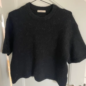 Svart stickad T-shirt - Säljer en svart stickad tröja från Gina Tricot i storlek S. Använd fåtal gånger och därav i superbra skick! Den är kortärmad och har en mysig, lite fluffig textur. Perfekt för höst och vår när du vill ha något bekvämt men ändå stilrent. Passar bra till både jeans och kjol!🤍