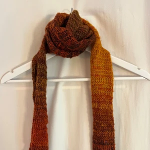 Stickad halsduk i höstfärger - Säljer en lång och mysig stickad halsduk i varma höstfärger från Urban Outfitters. Röd, orange, gul och brun. Passar perfekt för höst och vinter!
