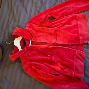 Röd hoodie från Juicy Couture - Säljer en supermjuk och snygg röd hoodie från Juicy Couture. Den har en dragkedja framtill och en skön huva. Perfekt för en chill dag eller en avslappnad utflykt. Passar bra till både jeans och leggings. 🧡