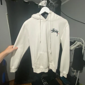 Vit Stussy hoodie   - Säljer en snygg vit hoodie från Stussy i bra skick. Den har en klassisk Stussy-logga både fram och bak. Perfekt för en avslappnad stil och passar till alla årstider. Size S