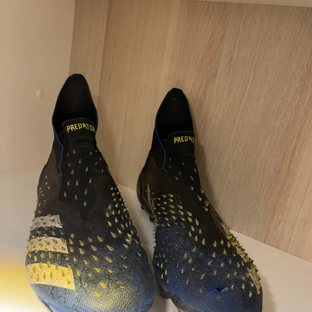 Säljer ett par Adidas Predator fotbollsskor i svart och gul färg. Skorna har en cool design med små gummitaggar för bättre bollkontroll. De är i bra skick och perfekta för fotbollsspel på gräs/konstgräs. Skor.