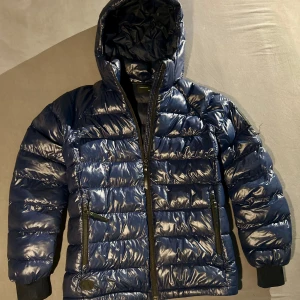 Blå pufferjacka från Peak Performance - Säljer en snygg blå pufferjacka från Peak Performance. Jackan är i mycket bra skick och perfekt för kalla dagar. Den har en glansig yta, dragkedja och långa ärmar med muddar. Perfekt för vintern och hösten! 💙