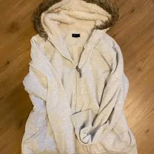 Mysig vit hoodie med dragkedja och fleecefoder. Den har en fluffig huva med pälsdetaljer som gör den perfekt för kyliga dagar. Perfekt för höst och vinter när du vill hålla dig varm och bekväm. 🧥❄️