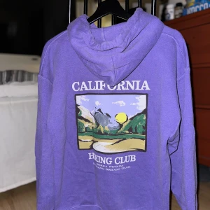 Baggy Hoodie med tryck från Urban Outfitters - Baggy och fet hoodie från Urban Outfitters. Har kommit till användning ett par gånger och är i bra skick. Den har ett tryck på baksidan vilket gör den unik.