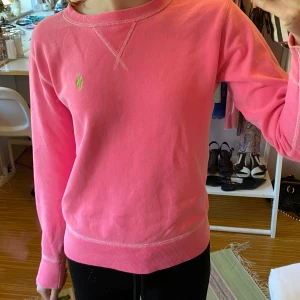 Rosa tröja från Polo Ralph Lauren - Säljer en superfin rosa tröja från Polo Ralph Lauren i storlek XS. Den har en klassisk design med ett grönt broderat märke. Tröjan är långärmad och perfekt för både vår och höst. Den är i bra skick och väldigt bekväm att ha på sig. 