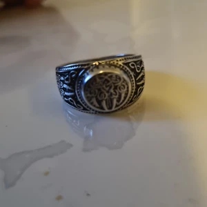 Silverring med detaljerat mönster - Säljer en snygg silverring med ett detaljerat mönster. Ringen har en rund platta med ett intrikat design som ger en vintagekänsla. Perfekt för att ge din outfit en unik touch!