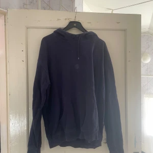 Mörkblå hoodie från Blåkläder - Säljer en mörkblå hoodie från Blåkläder i storlek L. Den är perfekt för kyliga dagar med sin mjuka och bekväma passform. Hoodien har en klassisk design med en stor ficka framtill och en justerbar huva. Perfekt för både vardag och arbete!