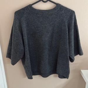 Mörkgrå stickad tröja - Mörkgrå stickad tröja med korta armar från lager 157 i storlek s. Nyskick då den är oanvänd o bara hängt i garderoben sen ja köpte den 