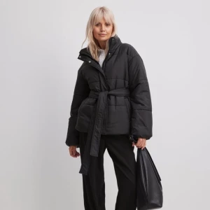 Svart pufferjacka med bälte - Snygg svart pufferjacka med bälte i midjan. Aldrig använd endast testad. Ny pris 799