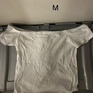 Vit offshoulder topp - Säljer en vit offshoulder topp i ribbat material. Perfekt för sommardagar med sin stilrena design och bekväma passform. Passar bra till både jeans och kjol.