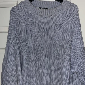 Ljusblå stickad tröja från Gina Tricot - Mysig ljusblå stickad tröja från Gina Tricot med dekorativa hålmönster framtill. Perfekt för kyliga dagar med sin bekväma passform och ribbade kanter.