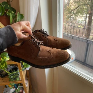 Bruna mockaskor från Sebago - Snygga bruna mockaskor från Sebago med klassisk snörning och stilren design. Perfekta för en elegant look. Sulan har bra grepp och är märkt med Sebago.