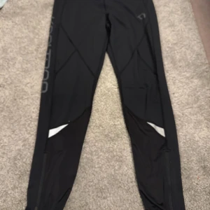 Svarta träningsleggings - Säljer ett par svarta träningsleggings med diskret logga och snygga sömdetaljer. Perfekta för gymmet eller löprundan. De har en tight passform och är tillverkade i ett stretchigt material för bästa komfort.