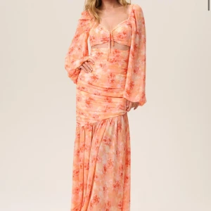 Porto dress adoore - Säljer adoores blommiga ”porto dress”, långklänning i orange och rosa toner. Klänningen har långa ärmar och en volangdetalj vid kjolen. Helt ny med prislapp kvar, säljer pga att den är precis för liten🩷 för referens är jag 156 cm och väger 60 kg.