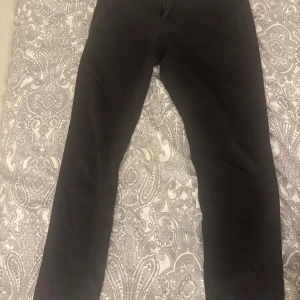 Svarta byxor från G-Star RAW - Snygga svarta byxor från G-Star RAW med en stilren design. Byxorna har en normal passform och är perfekta för en avslappnad men ändå uppklädd look. De har fickor både fram och bak samt en diskret logga vid midjan.