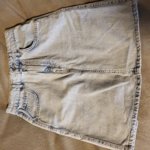 Ljusblå jeanskjol från Gina tricot - Snygg ljusblå jeanskjol från Gina tricot i klassisk femficksmodell. Kjolen har en kort längd och stängs med dragkedja och knapp framtill. Perfekt för en avslappnad stil.