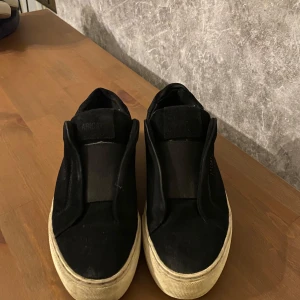 Svarta sneakers i mocka - Snygga svarta sneakers i mocka med en stilren design. Skorna har en vit sula som ger en fin kontrast till det svarta.