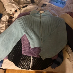 Ljusblå ribbad kofta från Zara - Säljer en ljusblå ribbad kofta från Zara med dragkedja och stor krage. Koftan har en mysig krage och är perfekt för kyliga dagar. Den är både stilren och bekväm att bära.