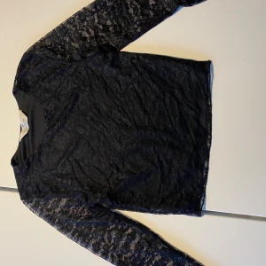 Svart spetsblus från H&M - Säljer en elegant svart spetsblus från H&M. Blusen har långa ärmar och ett vackert spetsmönster. 