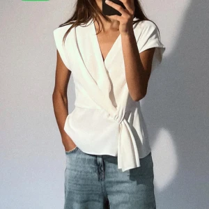 Vit omlottopp från Zara - Snygg vit omlottopp från Zara med korta ärmar och knytning i sidan. Perfekt för en stilren look.