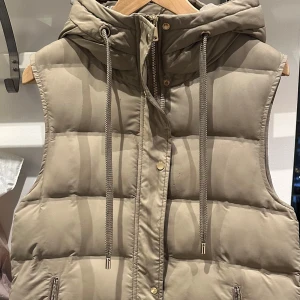 Beige dunväst  - Snygg beige dunväst med dragkedja och två fickor med dragkedja. Perfekt till hösten.                                             Kan fraktas eller hämtas i Uppsala 
