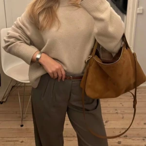 Brun axelväska i mocka - Snygg brun axelväska (ca 30x16cm)  i mocka liknande material med dragkedja och justerbar axelrem. Den har även en söt nallebjörnsnyckelring som detalj som medkommer 🧸helt nyskick