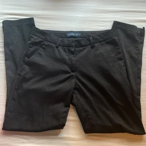Svarta mönstrade byxor från Stockh LM - Snygga svarta byxor med diskret mönster från Stockh LM. De har en klassisk passform med fickor fram och en bakficka. Perfekta för en stilren look.