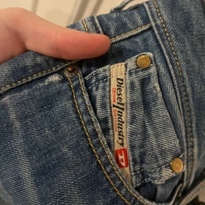 Blå jeans från Diesel - Säljer ett par snygga blå jeans från Diesel med klassisk femficksdesign och låg midja. Jeansen har en lätt slitning för en cool look och är perfekta för en avslappnad stil.