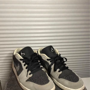 Nike Air Jordan sneakers 1 low - Snygga Nike Air Jordan sneakers i svart och grått med broderade detaljer. Skorna har en klassisk snörning och en bekväm passform. Perfekta för en stilren look.. Har ej användning av dem då jag köpt nya och dem bara ligger i hyllan. Använt ett par gånger. Hör av er!