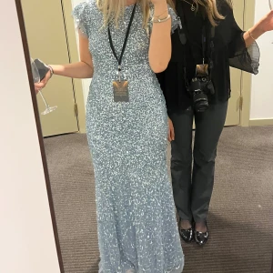 Glittrig blå balklänning  - Säljer den här snygga balklänningen från Maya Deluxe (köpt vid Bubbelroom för ett par år sedan). Klänningen är blå och har glittriga detaljer, öppen rygg och en liten puffärm samt är figursydda . Klänningen är endast använd en gång!! 