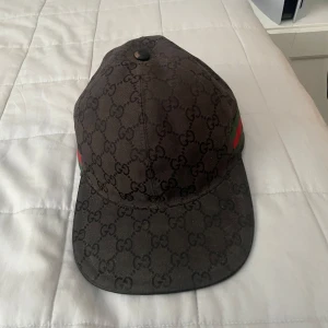Gucci kepsar  - Två stilrena kepsar från Gucci med det ikoniska monogrammönstret. Den ena kepsen är svart med gröna och röda detaljer, medan den andra har ett tigertryck på framsidan. Båda kepsarna har justerbar passform och är perfekta för att ge en lyxig touch till din outfit. 1700 kr styck eller 3000 för båda. Båda 2 är dom gamla modellerna som sitter bättre på huvudet och inte går och köpa längre 