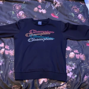 Svart tröja från Champion - Säljer en svart tröja från Champion med färgglad logotyp i flera nyanser på bröstet. Säljer den då den inte passar mig längre. Perfekt till barn 11-13. Sjukt skön och passar väldigt bra. Äkta såklart