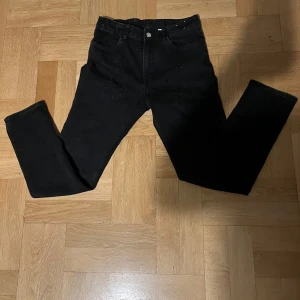 Svarta jeansbyxor - Snygga svarta jeansbyxor med en klassisk femficksdesign. De har en knapp och dragkedja framtill och är perfekta för en stilren look. Passformen är straight och de är tillverkade i ett slitstarkt material. Priset kan diskuteras
