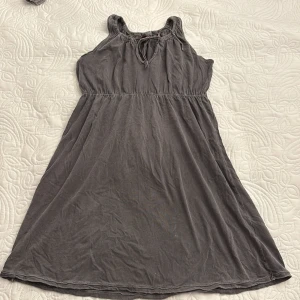 Grå ärmlös klänning - Säljer en enkel och bekväm grå ärmlös klänning i 100% bomull. Klänningen har en knytning vid halsen och en elastisk midja för en smickrande passform. Klänningen är väldigt elastiskt och därmed kan de med storlek M säven använda.
