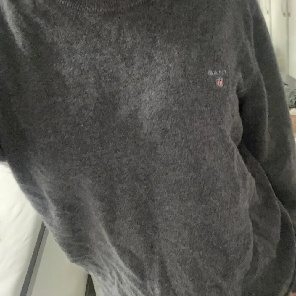 (HÄRR TRÖJA) Säljer en stilren grå tröja från GANT med broderad logotyp på bröstet. Tröjan har långa ärmar och en klassisk rund halsringning. Perfekt för en avslappnad och snygg look.. Neuletakit & Villapaidat.