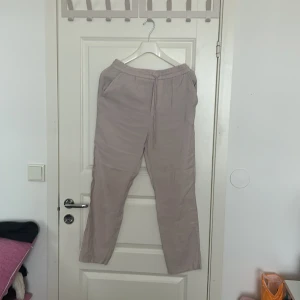 Beige byxor från Zara - Säljer ett par beige byxor från Zara med elastisk midja och snörning. Byxorna har en avslappnad passform och är perfekta för en bekväm stil. De har fickor både fram och bak.