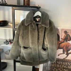 Fluffig Jacka - Så söt fluffig (faux fur) jacka från HM 🪩Grå/grön i färgen. OBS, den är jämn i färgen! På bilderna ser det ut som att den är lite mörkare uppe och nere men är endast pga skuggor! 🌟 Passar ca XS-M beroende på hur man vill att den ska sitta! 💃🏽skriv för mer bilder ❤️‍🔥